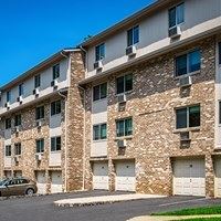 A tan car is parked in front of a tan building with white trim.